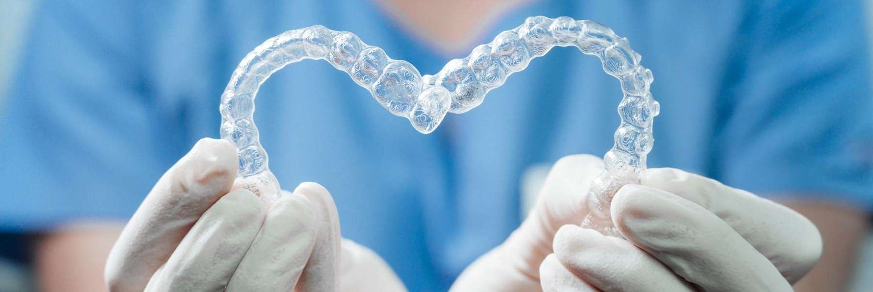 A dentist holding Invisalign trays in the shape of a heart | Scottsdale