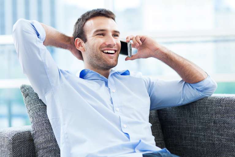 A laughing man on the phone with his scottsdale dentist