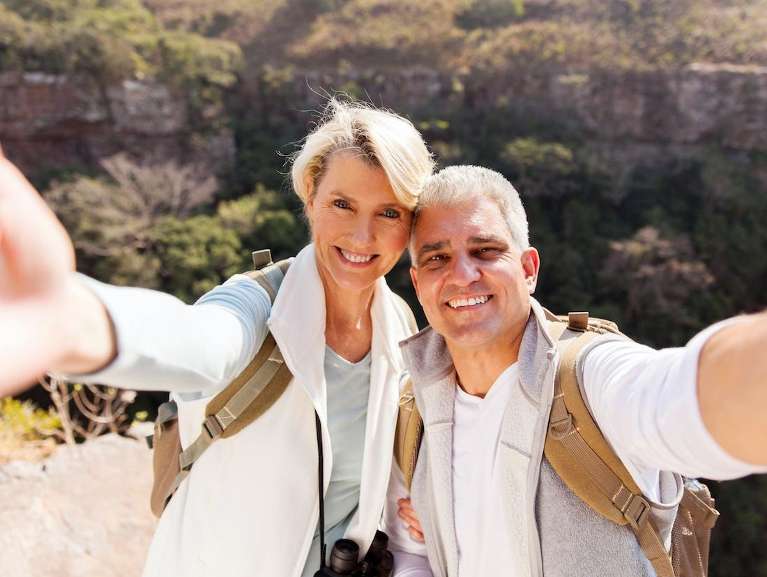 A smiling couple taking a selfie in front of a canyon