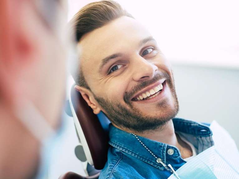 A smiling man talking to his dentist