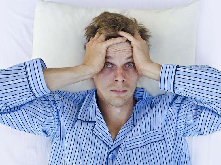 A man in bed with sleep apnea having trouble sleeping
